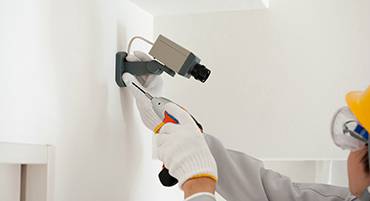 טכנאי מתקין מצלמת אבטחה על קיר